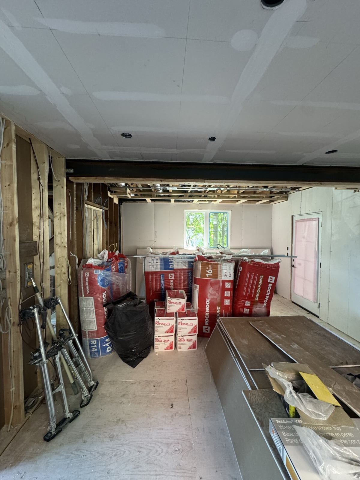 Boarded ceiling in a room with batt insulation stacked below