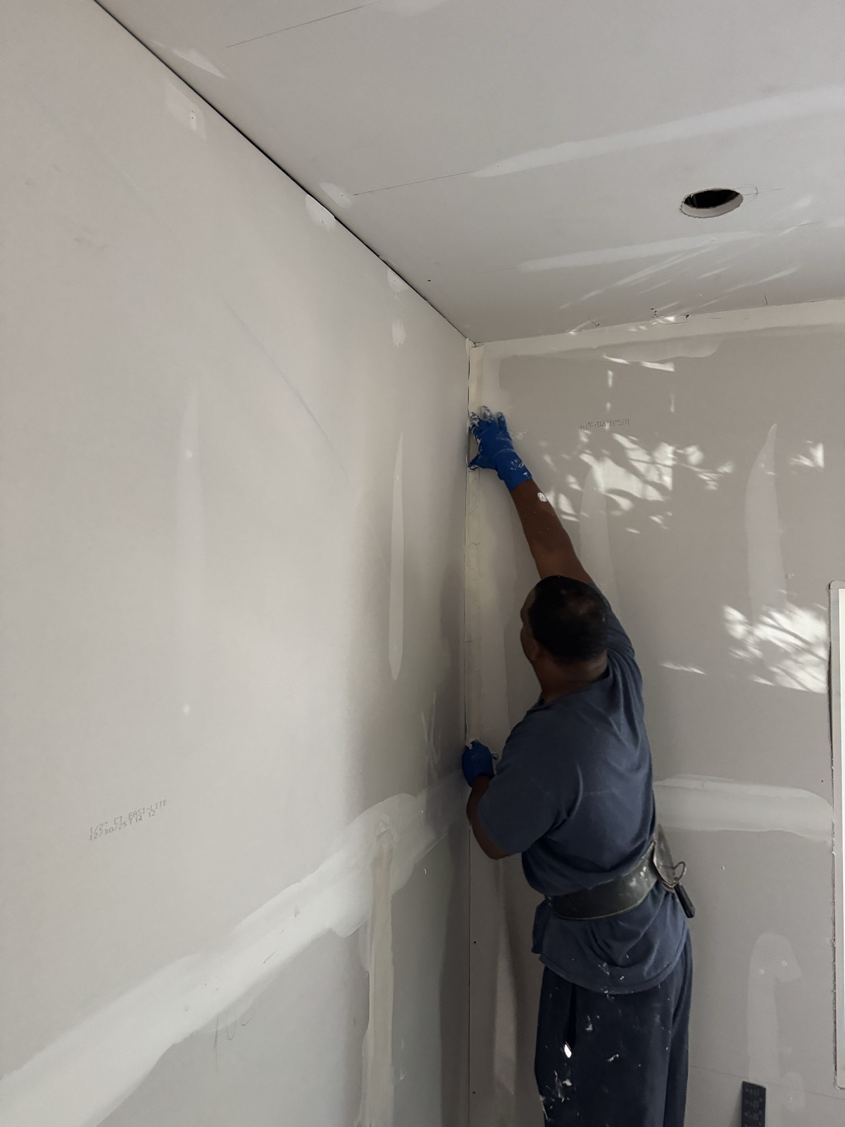 Gary taping an inside corner where the wall meets the ceiling
