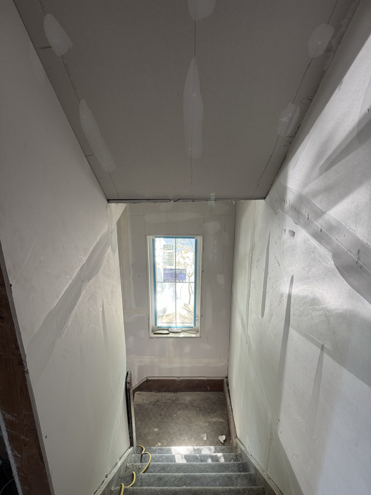 Stairwell with taped and coated drywall walls and ceiling