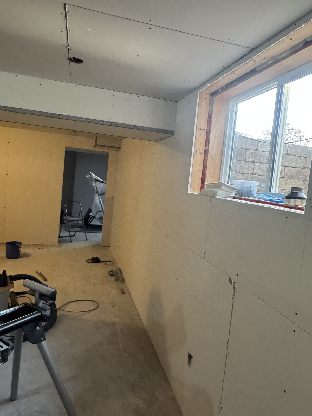 The same basement room with drywall boarded, joints not yet taped